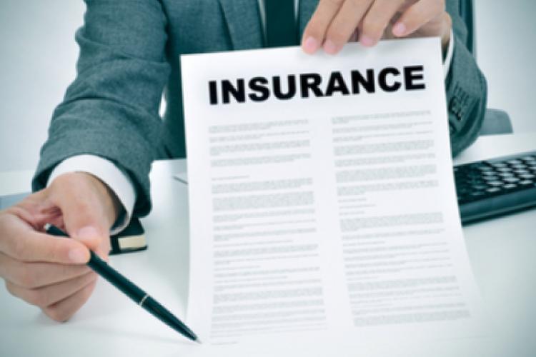 A business person holding a paper in one hand, which says "Insurance" at the top and a pen in the other hand