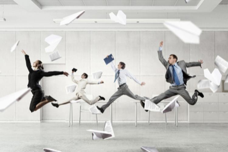 Four business people jumping in the air with paper airplanes flying around them